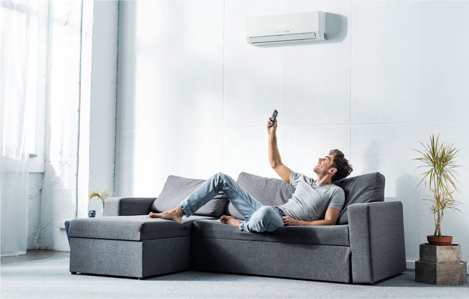 A man setting the thermostat of his non inverter aircon