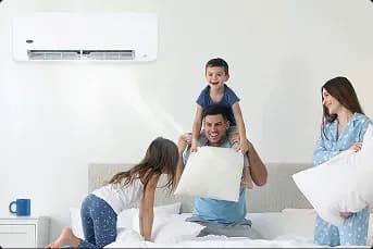 A family playing together on the bed with Carrier split type aircon providing quick cooling