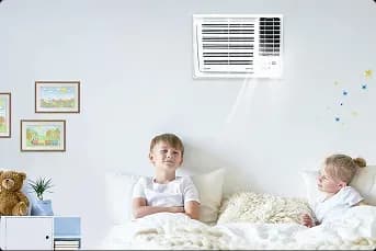Two siblings relaxing on the bed with cool air produced by their small compact aircon 